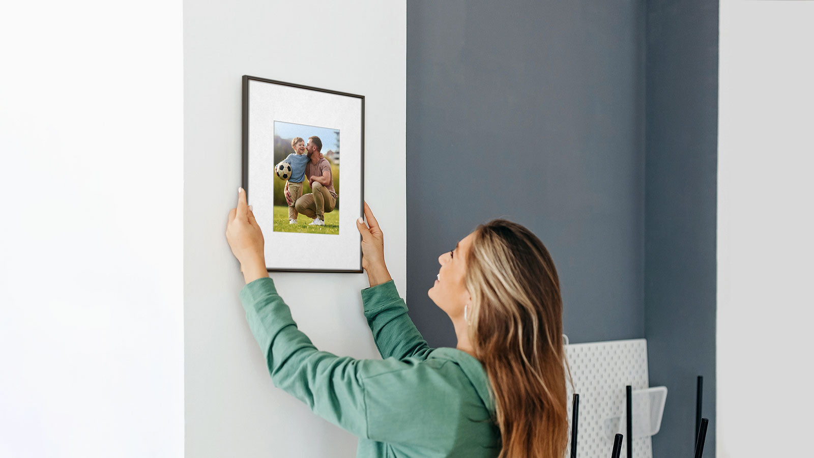 Woman hanging an Aluratek 13.3" ePaper frame on wall