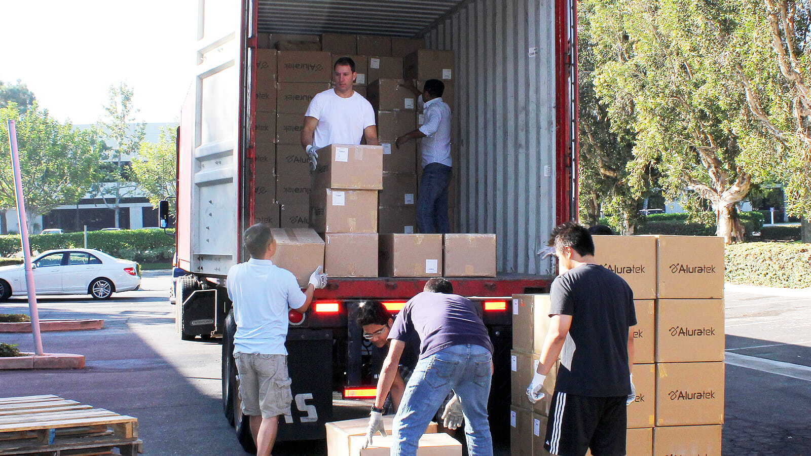 Aluratek Celebrating 20 Years in Pictures - Men unloading a truck with boxes stacked around them