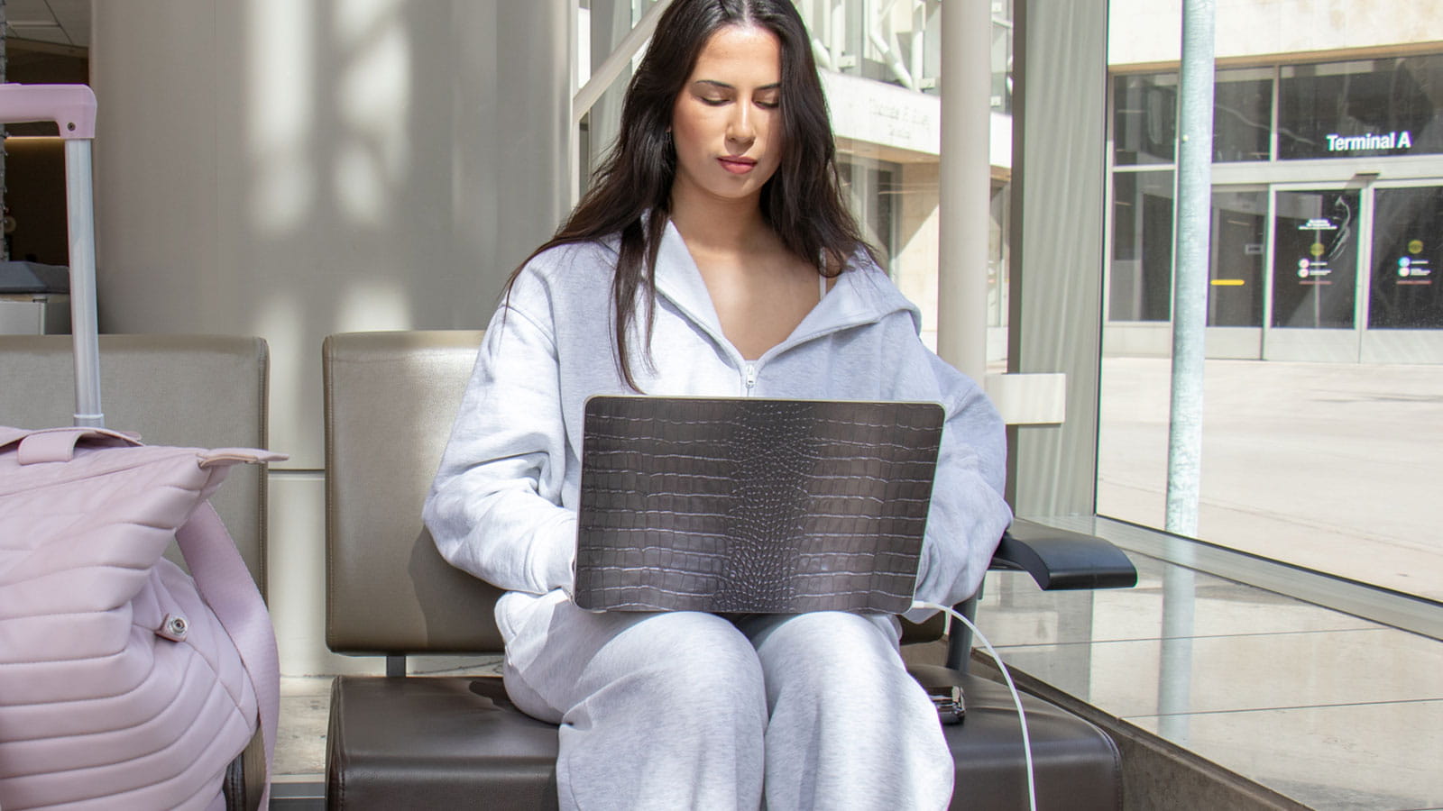 Travel Tech You Can't Live Without - Woman sitting in an airport lobby using her laptop