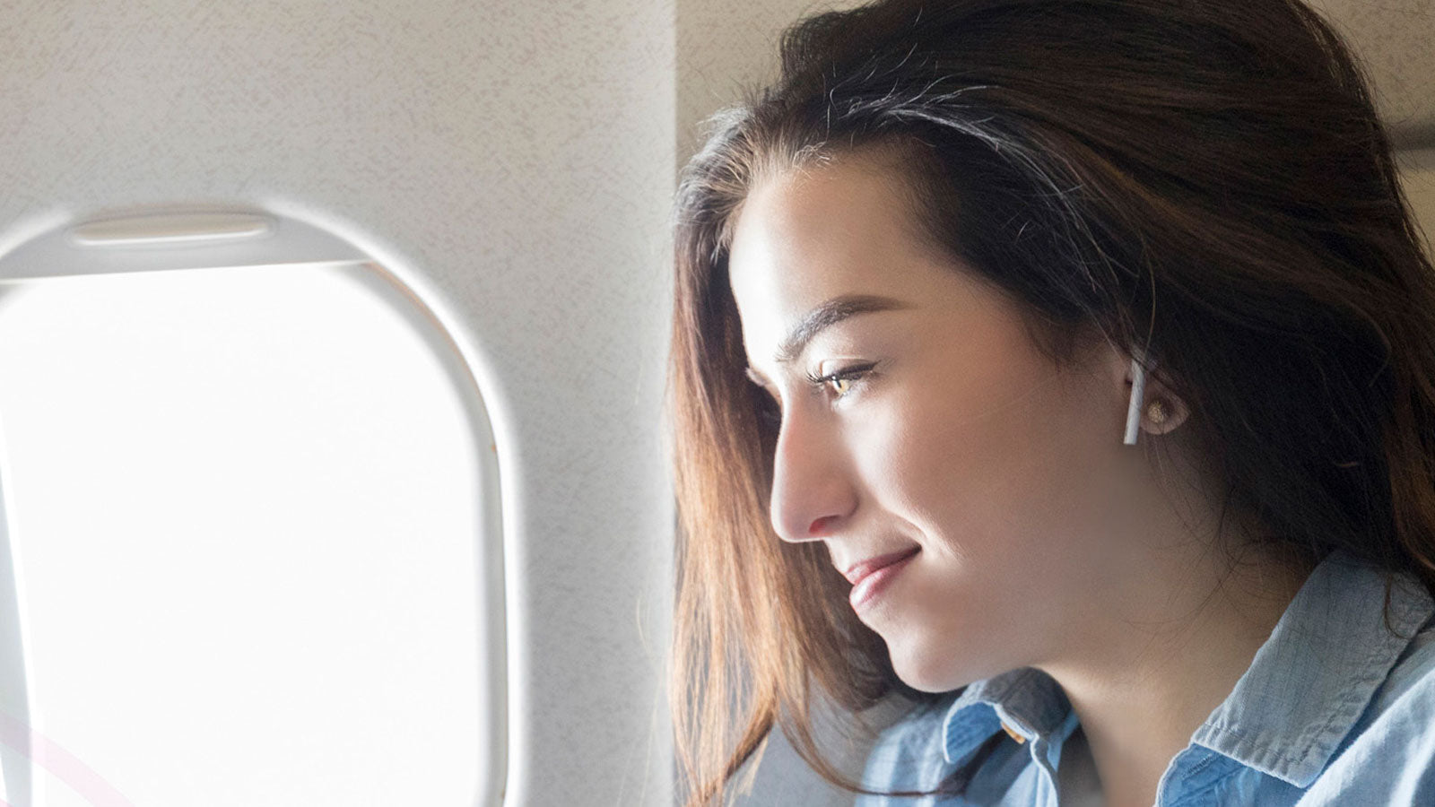 Girl listening to ear pods with Aluratek AirStream on plane