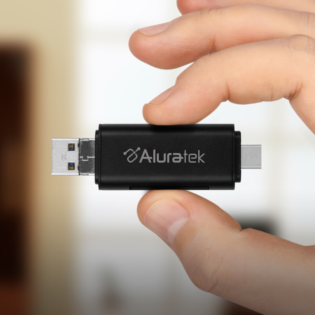A hand holding a USB card reader